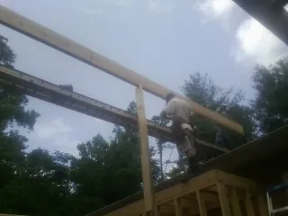 Carpenter setting a ridge beam over a new addition frame — Ice Dam Removal by Roofing Brothers in Cummaquid