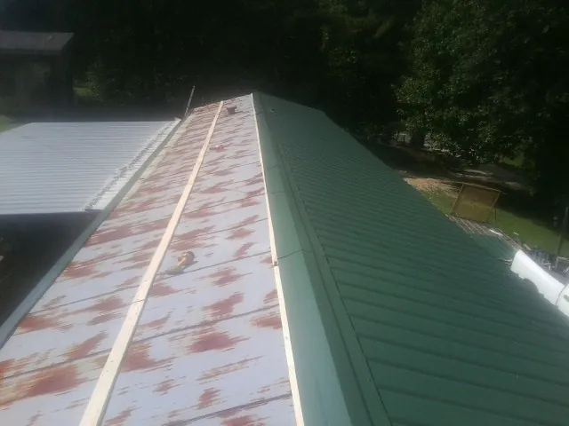 Old rusted panels beside newly installed green metal roofing — Wind Damage Roof Repair by Roofing Brothers in Cummaquid