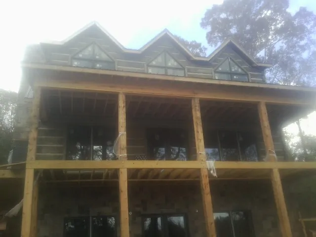 Dormers and porch framing on a large log home under construction — Roof Coating work by our crew in Cummaquid