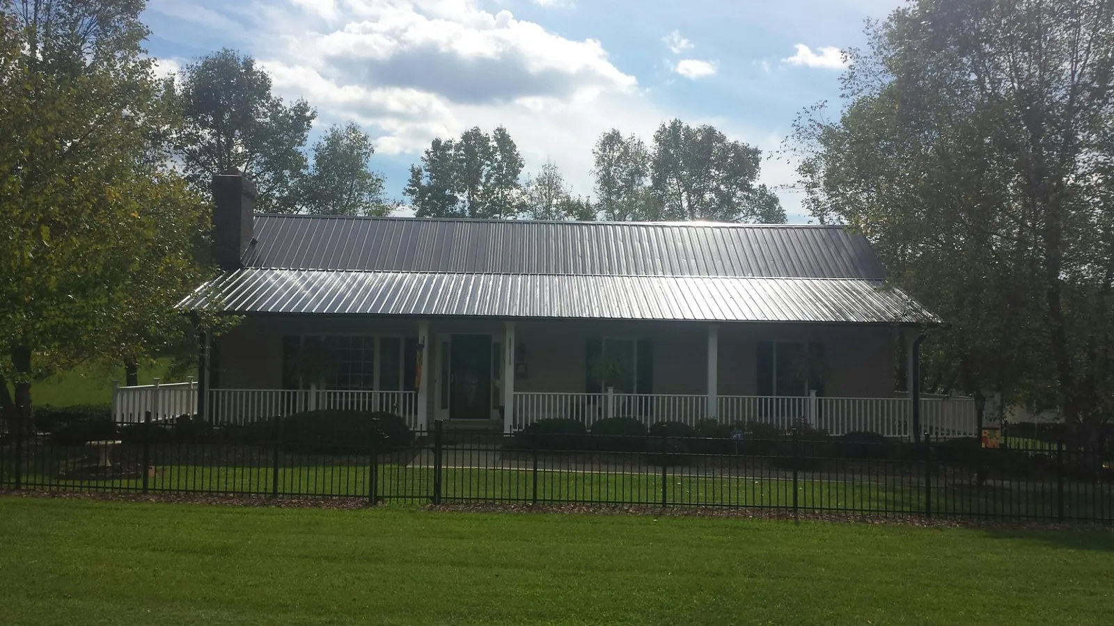 Gray metal roof on a brick ranch with a full width front porch — Gutter Guard Installation work by our crew in Cummaquid