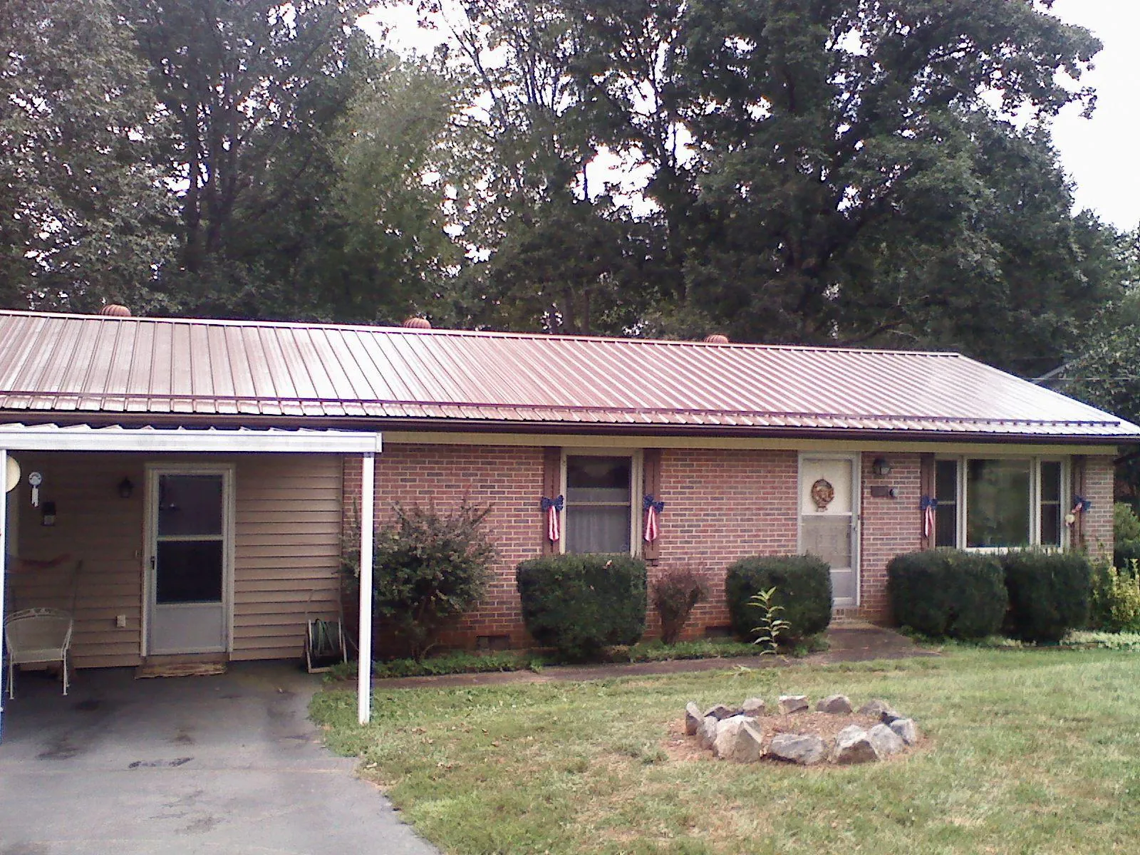 Bronze metal roof and carport on a brick ranch home — Roof Repair work by our crew in Cummaquid