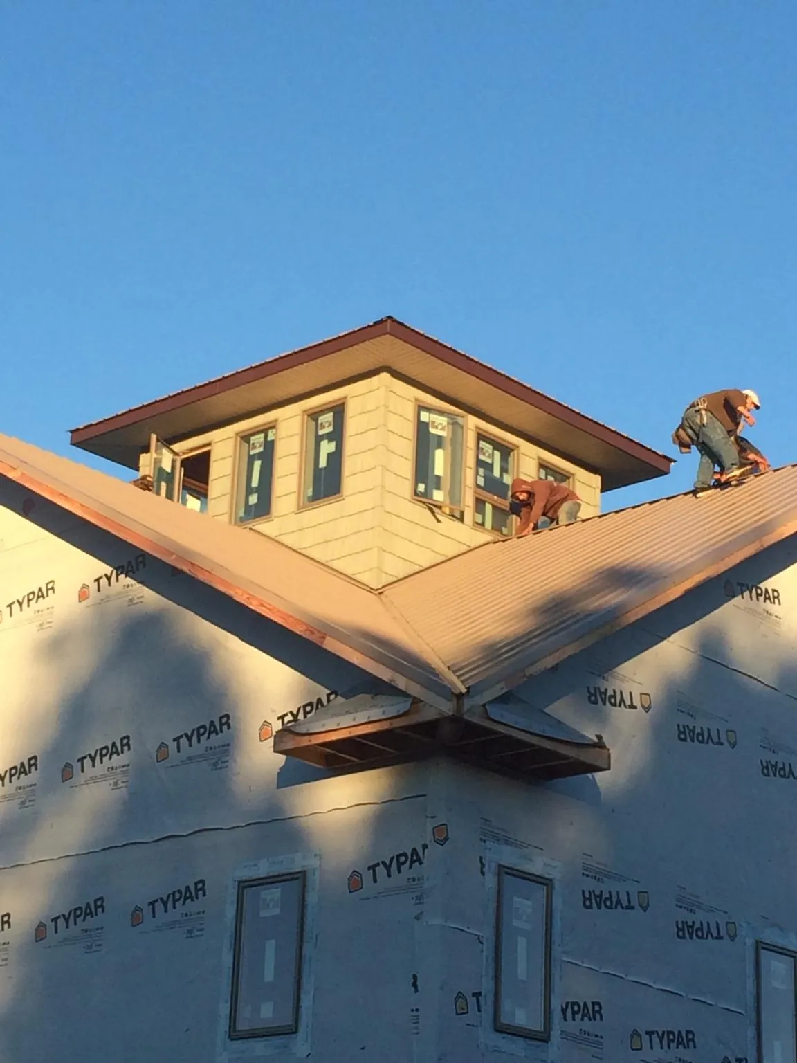 Roofers working around a rooftop cupola on a new metal roof at sunset — Roof Waterproofing in Cummaquid by Roofing Brothers